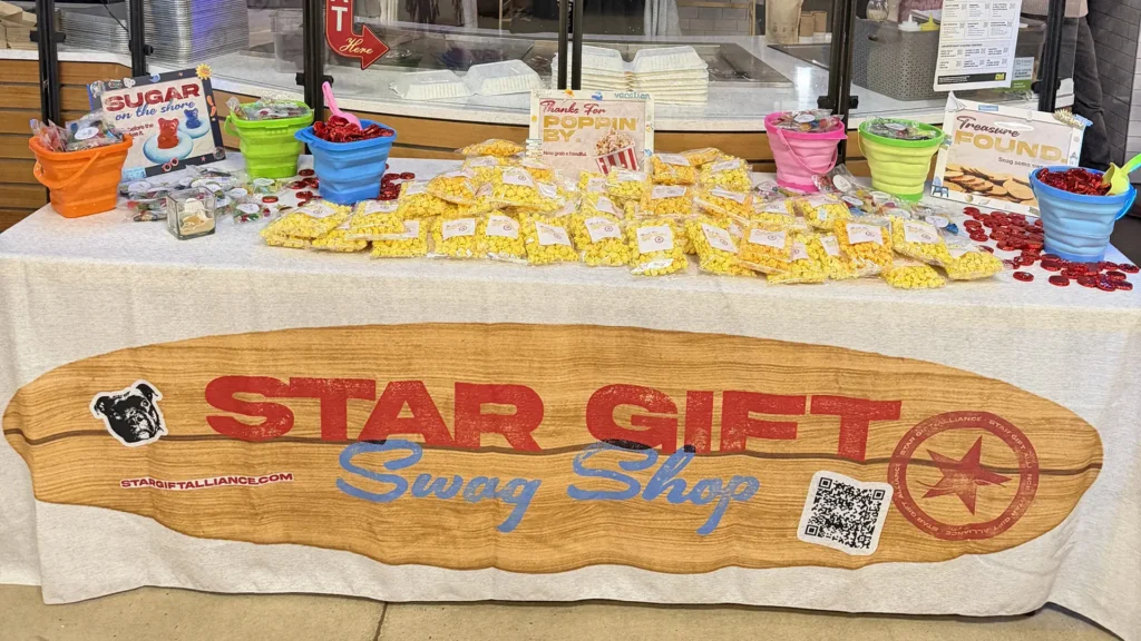 Event swag display table with branded popcorn, candy buckets, and custom Star Gift signage for experiential event branding setup