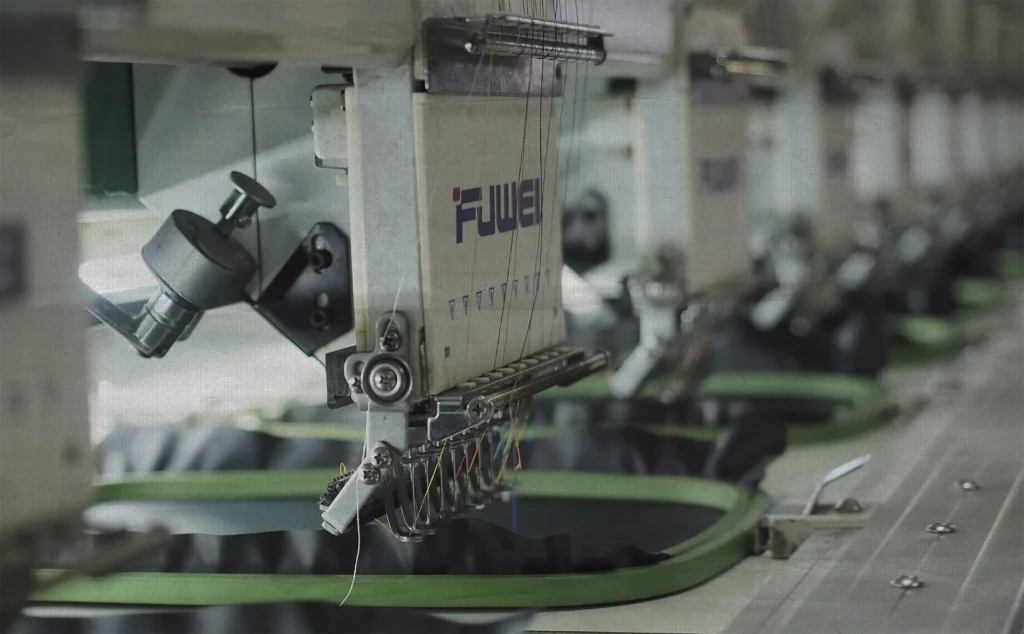 Custom merch embroidery machine stitching designs on fabric at Star Gift Alliance production facility.